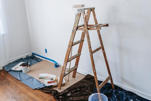 a ladder and paint supplies set up against a wall